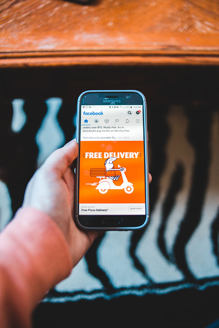 image showing a hand holding a mobile phone with a facebook ad on it