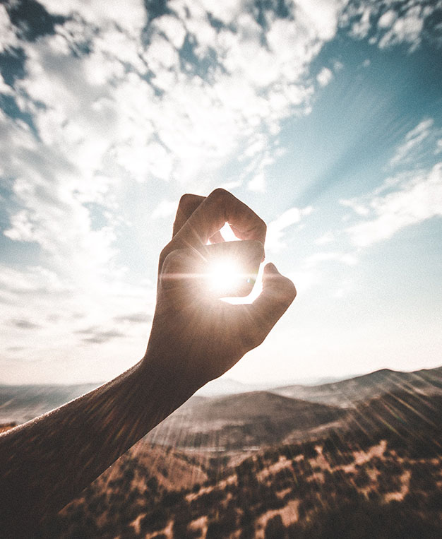 image of a hand curled with the sun shining through the middle